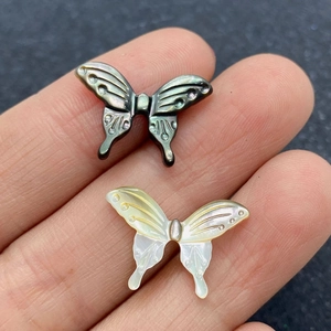 Détail macro de perles papillon en nacre naturelle sculptées pour la création de bijoux