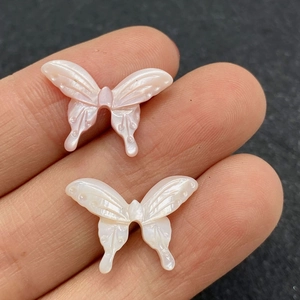 Détail macro de perles en nacre sculptées en forme de papillon avec un éclat iridescent
