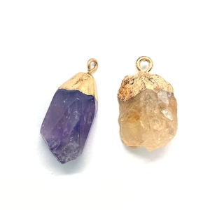 Macro shot of natural purple amethyst and yellow quartz pendants with gold metal plating
