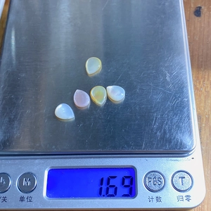 Macro shot of natural teardrop sea shells on digital scale for jewelry making