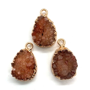 Three teardrop natural crystal druzy pendants with gold plated edges on white background