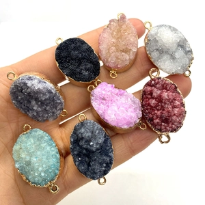Oval druzy stone connectors with gold edges in eight colors held in hand for scale