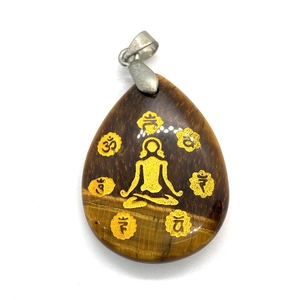 Macro shot of tiger eye teardrop pendant with gold yoga meditation engraving detail