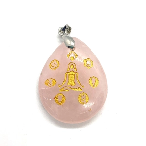 Macro shot of pink quartz teardrop pendant with golden yoga engraving and silver bail