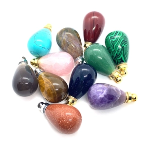 Macro detail of various teardrop gemstone pendants with metallic screw caps on white background
