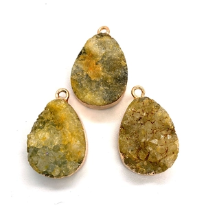 Detailed close-up of three teardrop natural stone pendants with rose gold metallic edging