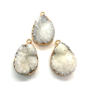 Three teardrop natural crystal druzy pendants with gold plated edges on white background
