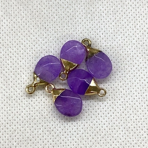 Macro shot of five faceted purple teardrop stone pendants with gold metal caps for DIY jewelry