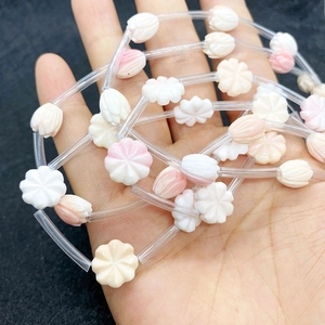 Gros plan de perles fleurs sculptées de 12 mm en blanc et rose pour bijoux DIY
