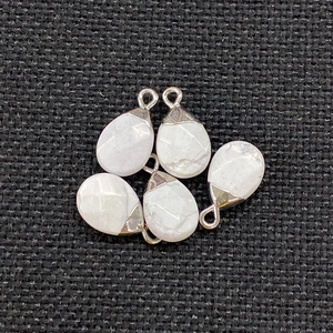 Detailed view of five teardrop marble stones with silver metal caps on dark background