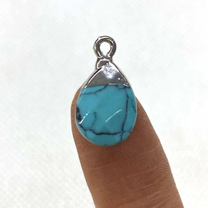Waterdrop turquoise pendant with silver metal edge shown on finger for scale