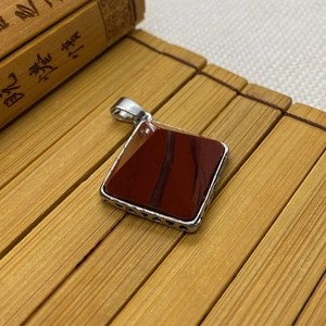 Détail macro du pendentif en agate rouge avec motif coeur ajouré en argent poli