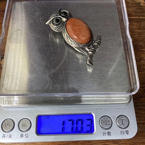 Detalle de colgante de búho en una báscula electrónica con un peso de 17,03 gramos