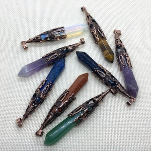 Natural crystal hexagonal pillar pendants with vintage bronze caps on white fabric