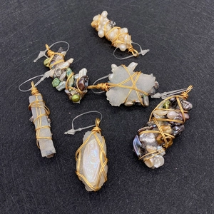 Detailed macro view of handmade wire wrapped baroque pearl and raw stone pendants