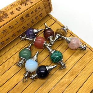 Assorted natural gemstone dowsing pendulums with silver cone tips on a bamboo mat