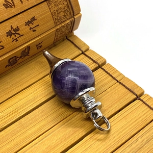 Macro shot of polished spherical purple amethyst pendulum pendant with silver metal fittings