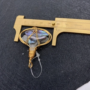 Macro view of handmade gold wire wrapped baroque pearl and crystal pendant measuring 38mm