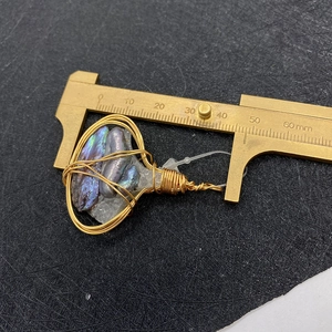 Macro view of handmade wire wrapped pendant with purple stones and size caliper