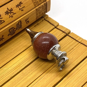 Macro shot of goldstone gemstone pendulum pendant on a natural bamboo mat background