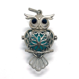 Macro detail of owl cage pendant with green stone bead and black gem eyes