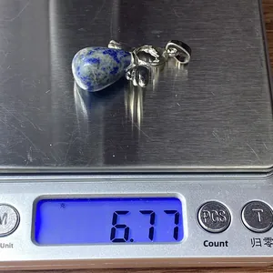 Gedetailleerde gewichtsmeting van 6,77 g voor de blauwe stenen vleugel hanger op de weegschaal