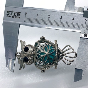 Measuring turquoise-colored stone owl pendant width using a professional digital caliper