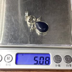 Dettaglio che mostra il peso di 5,08g del ciondolo a goccia in pietra arenaria blu e ali