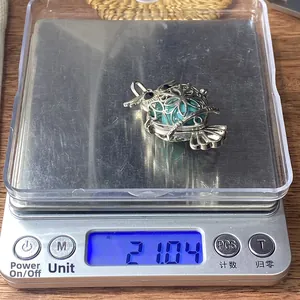 Detailed view of silver owl pendant with green stone bead on digital scale weighing 21.04g
