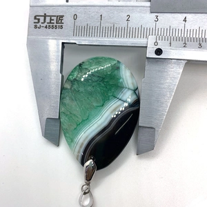 Macro view measuring the 31x44mm green agate teardrop pendant width with a caliper tool