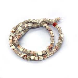 Primer plano de cuentas cuadradas de piedra natural con texturas terrosas para joyería DIY