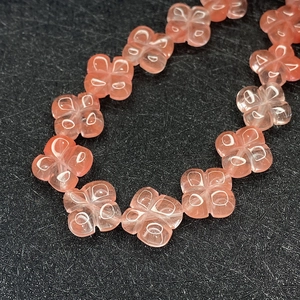 Vista macro di perline a forma di quadrifoglio rosa traslucido per gioielli fai-da-te