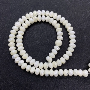 Détail macro de perles de nacre naturelle blanches en forme de disque avec un éclat iridescent