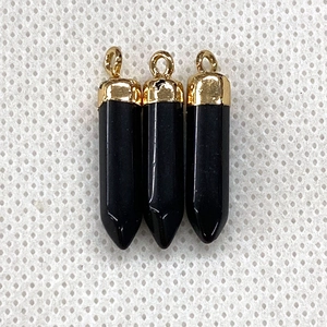 Detailed macro view of three black hexagonal prism pendants with golden metal caps