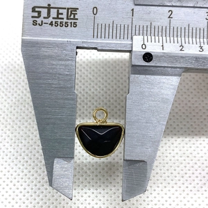 Macro detail of a 12mm semi-circular black natural stone pendant with gold plating