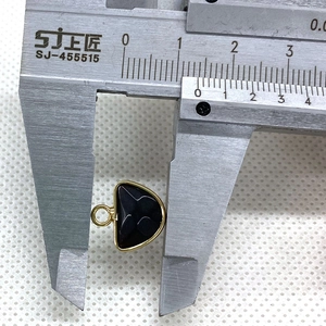 Macro shot showing dimensions of a semi-circular black agate pendant with gold cross detail