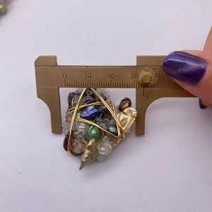 Dettaglio del ciondolo con perle barocche e misura della larghezza con calibro