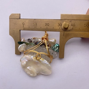 Dettaglio di un ciondolo di perle fatto a mano da 34mm con finiture in filo dorato