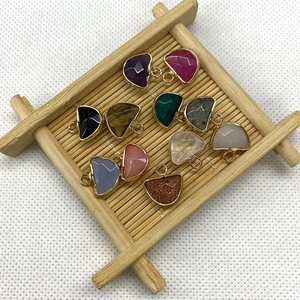 Natural semi-circular gemstone pendants with gold-plated edges on a textured background
