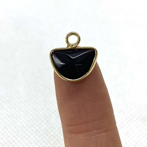 Semicircle labradorite stone pendant with gold-plated bezel held on a fingertip