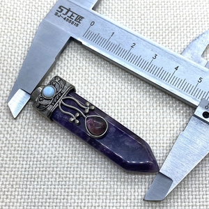 Detail view of amethyst hexagonal prism pendant with vintage engraved metal cap and jewels