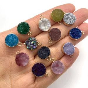 Zwölf farbenfrohe 13x16mm runde Druzy-Kristallanhänger mit Goldrand in der Hand