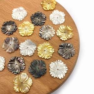 Detailansicht von 20mm geschnitzten Muschelperlen in Blumenform auf einem Holztablett