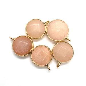 Close-up of faceted round sunstone pendants with gold frames for DIY jewelry making