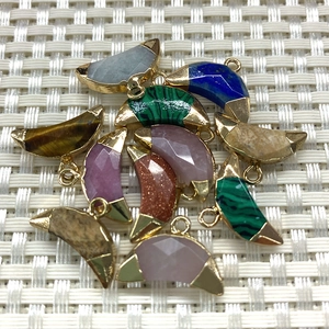 Vue détaillée de pendentifs en pierre demi-lune avec bords dorés et anneaux en métal