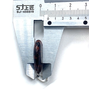 Thickness measurement of teardrop stone pendant with digital caliper showing 7.5mm depth