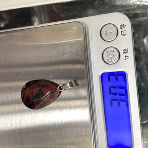 Macro view of mahogany obsidian teardrop pendant on an electronic scale weighing 3.03g