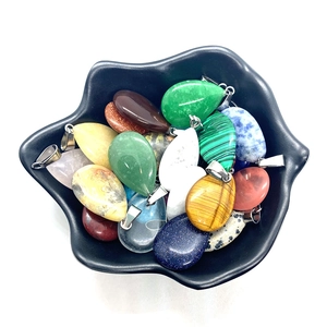 Polished semi-precious stone teardrop pendants on a Hamsa hand tray for DIY necklaces