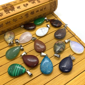 Teardrop gemstone pendants set in malachite and quartz with silver bails on bamboo mat