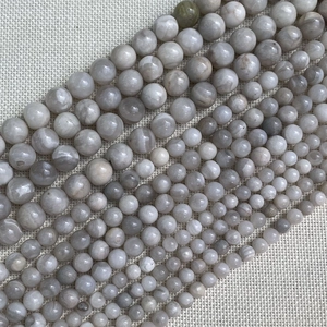 Vista detallada de cuentas de piedra natural blanco grisáceo con textura jaspeada para joyería